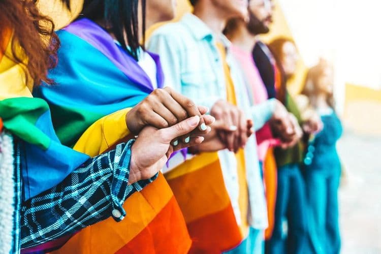 Image of people holding hands with and LGBTQ+ flag