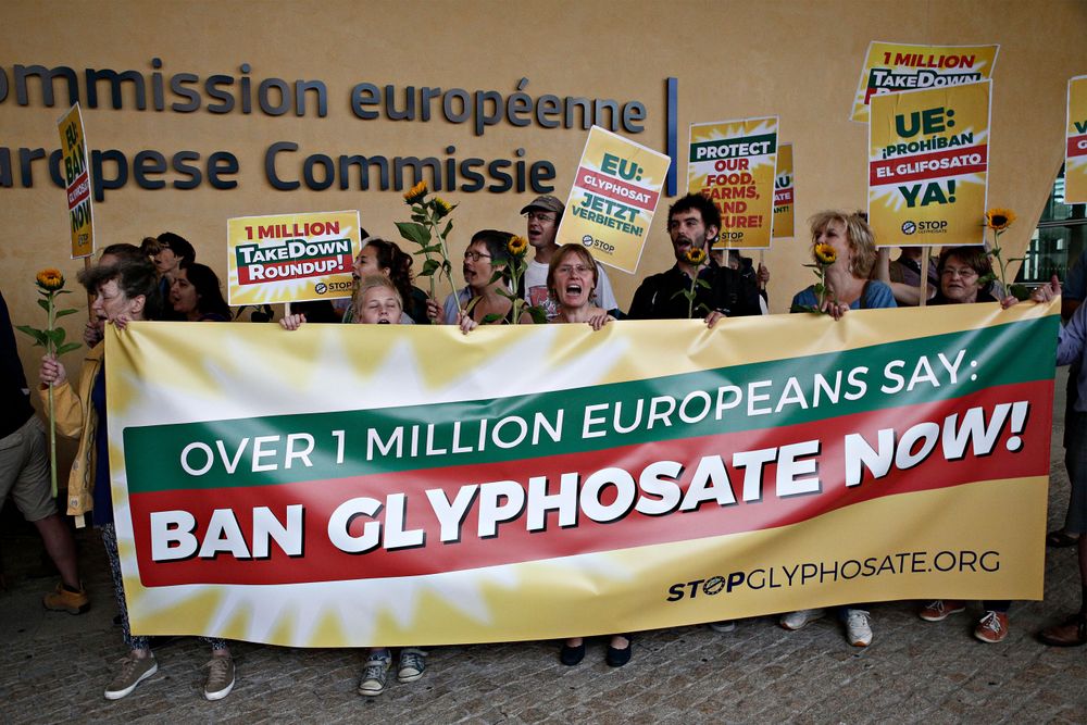 Menschen stehen hinter einem Transparent mit der Aufschrift "Ban glyphosate now!"