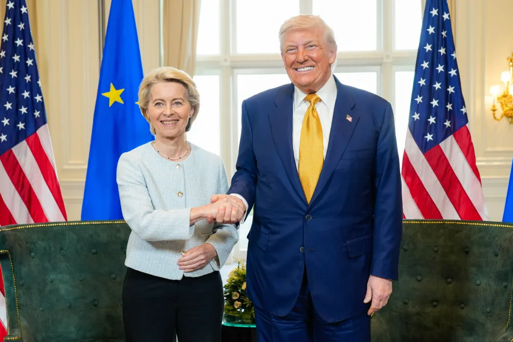 Une photo du président américain Trump et de la présidente de la Commission européenne von der Leyen se serrant la main.