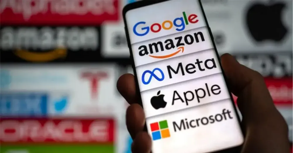 Une main tient un téléphone portable orné des logos des géants de la tech.