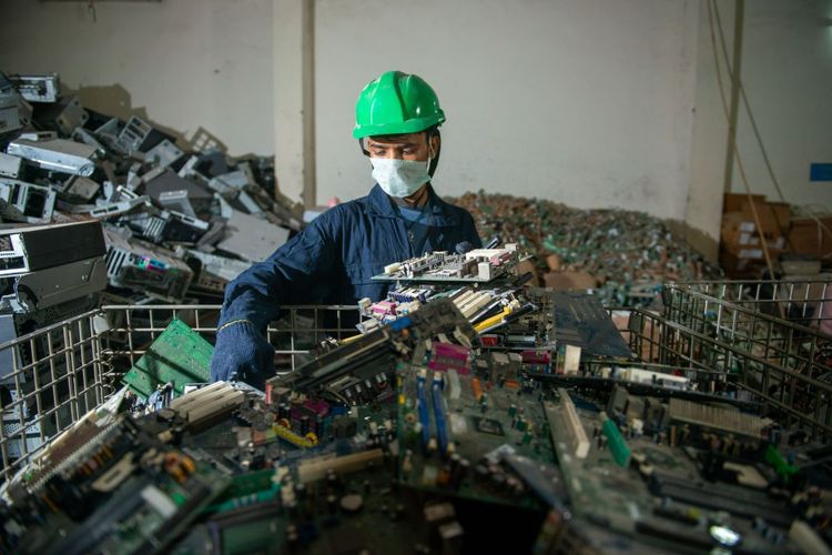 Una persona che smista una montagna di rifiuti elettronici