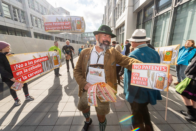 Man in traditional German clothes hands out No Patents flyers