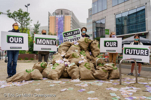 Eine Gruppe von Aktivistinnen und Aktivisten stehen um einen Haufen Geldsäcke. Scheine wirbeln im Wind. Die Schilder sagen: Our Money Our Future - Unser Geld unsere Zukunft. Die Anzahl der Unterschriften ist mit 1,3 Millionen angegeben. Sie sind in Brüssel.
