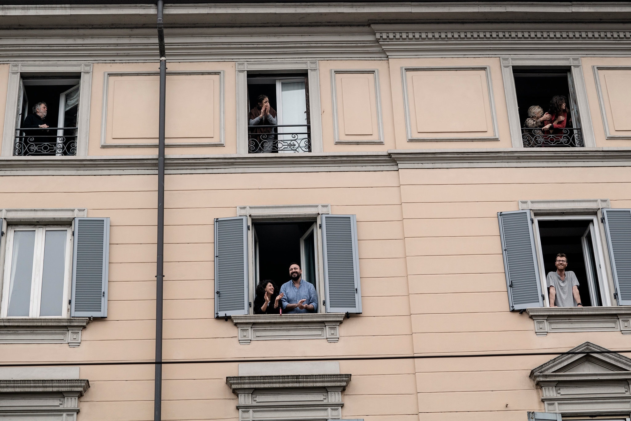 Close up of apartment balconies, people standing and clapping